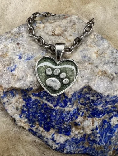 Colgante de plata en forma de corazón con una huella de mascota